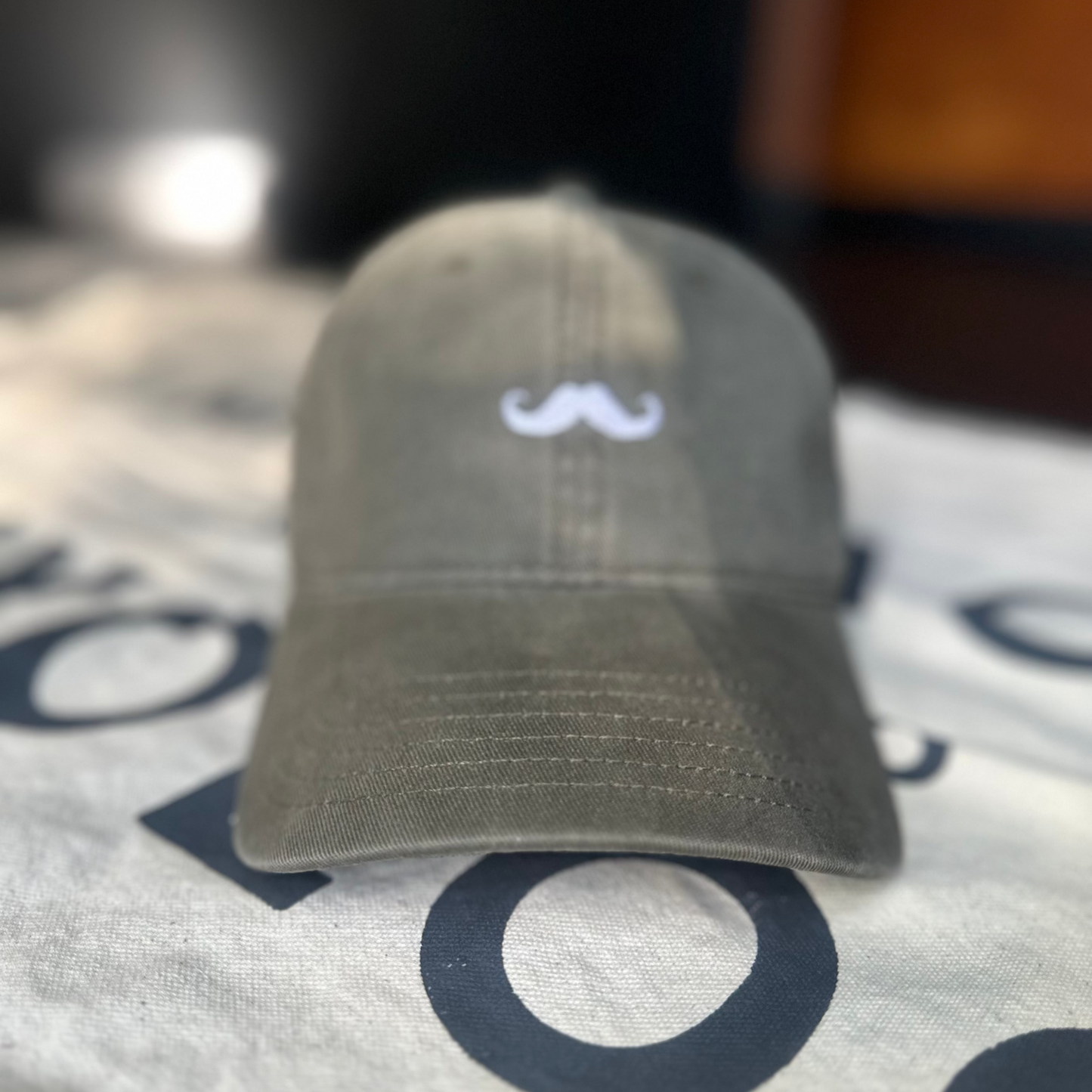 Gray cap with a logo on a white surface with black text